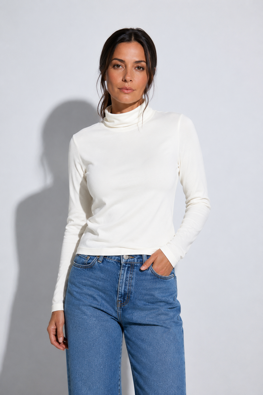 A woman wearing a fitted white long-sleeve turtleneck top