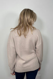 Back view of a woman wearing a fitted 3 button beige knitted cardigan