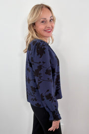woman wearing a blue floral blouse with lace trim