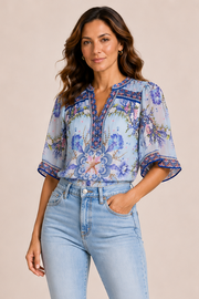 Woman wearing a blue floral blouse with 3/4 length flowy sleeves 