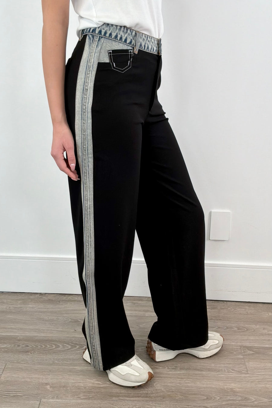 Side view of Woman wearing black dress pants with accents of light indigo denim