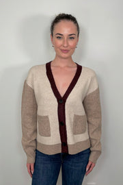 Front view of woman wearing a colour block beige and burgundy cardigan with pockets
