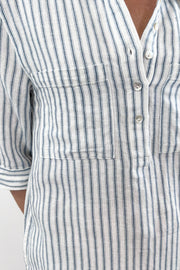 Woman wearing a striped shirt dress with a collar, buttoned neckline, and three-quarter sleeves, closeup