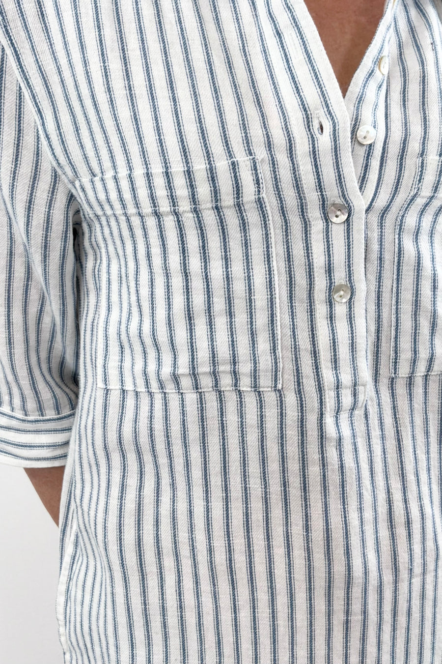 Woman wearing a striped shirt dress with a collar, buttoned neckline, and three-quarter sleeves, closeup