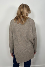 Back view of woman wearing a greige asymmetrical sweater 