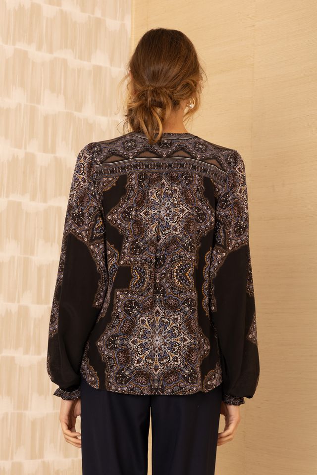 Back view of woman wearing a black patterned v-neck long blouson sleeve blouse