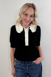 Woman wearing a black polo with white collar