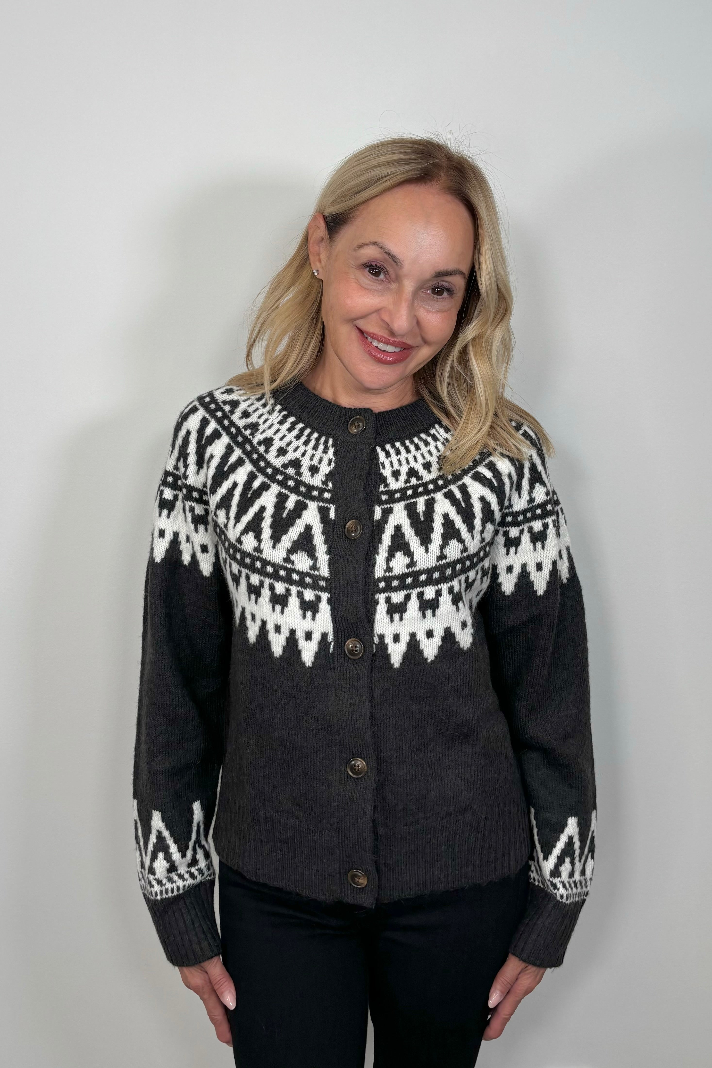 woman wearing a dark gray button up cardigan with detailing on the op and cuffs