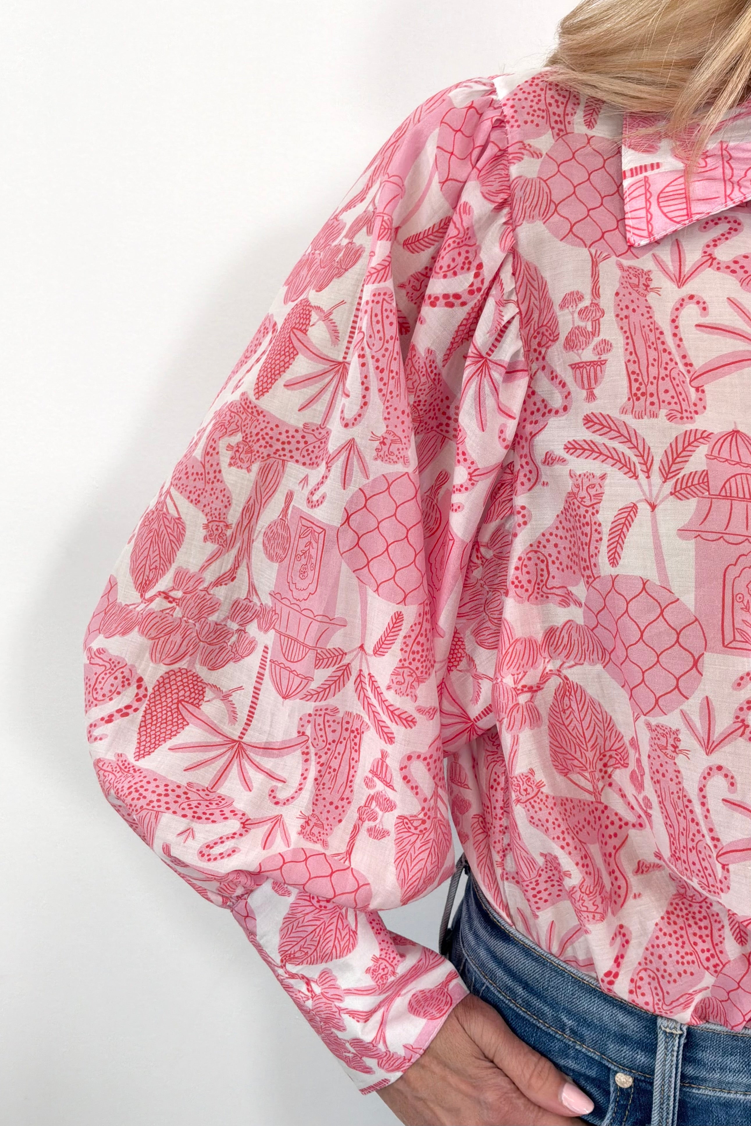 Close up of Woman wearing pink and white long sleeve blouse with jungle print all over
