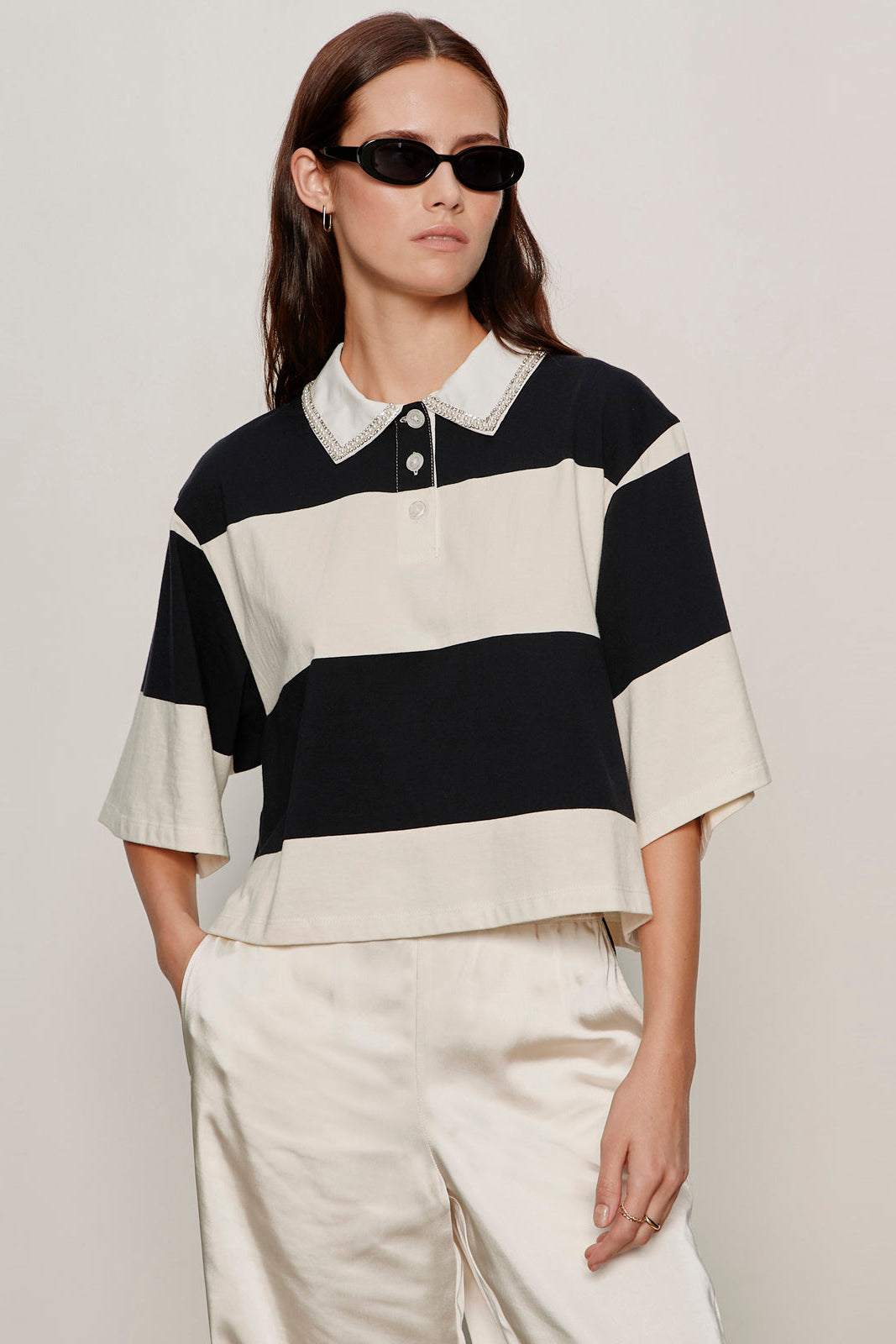 woman wearing a black and white striped half sleeve polo with embellished collar