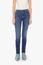 Woman wearing a white tank top and blue mid-rise, straight leg jeans on a white background
