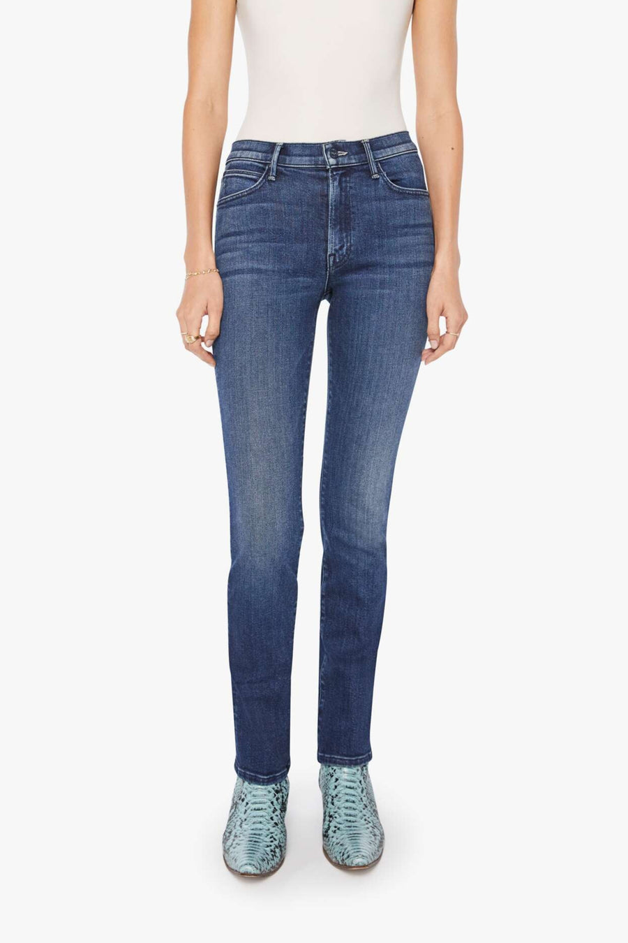 Woman wearing a white tank top and blue mid-rise, straight leg jeans on a white background
