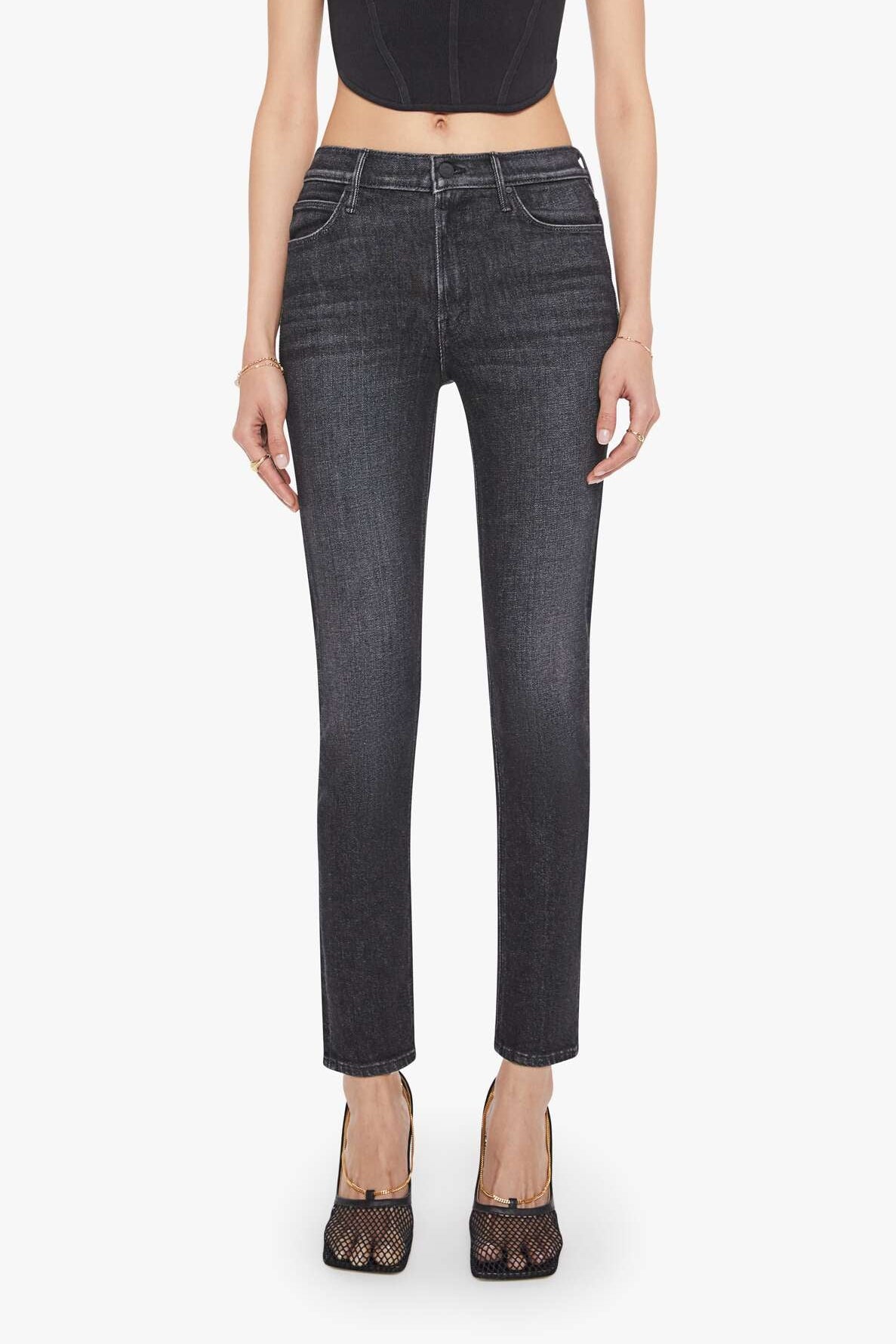 Woman wearing black tank top and dark jeans on a white background