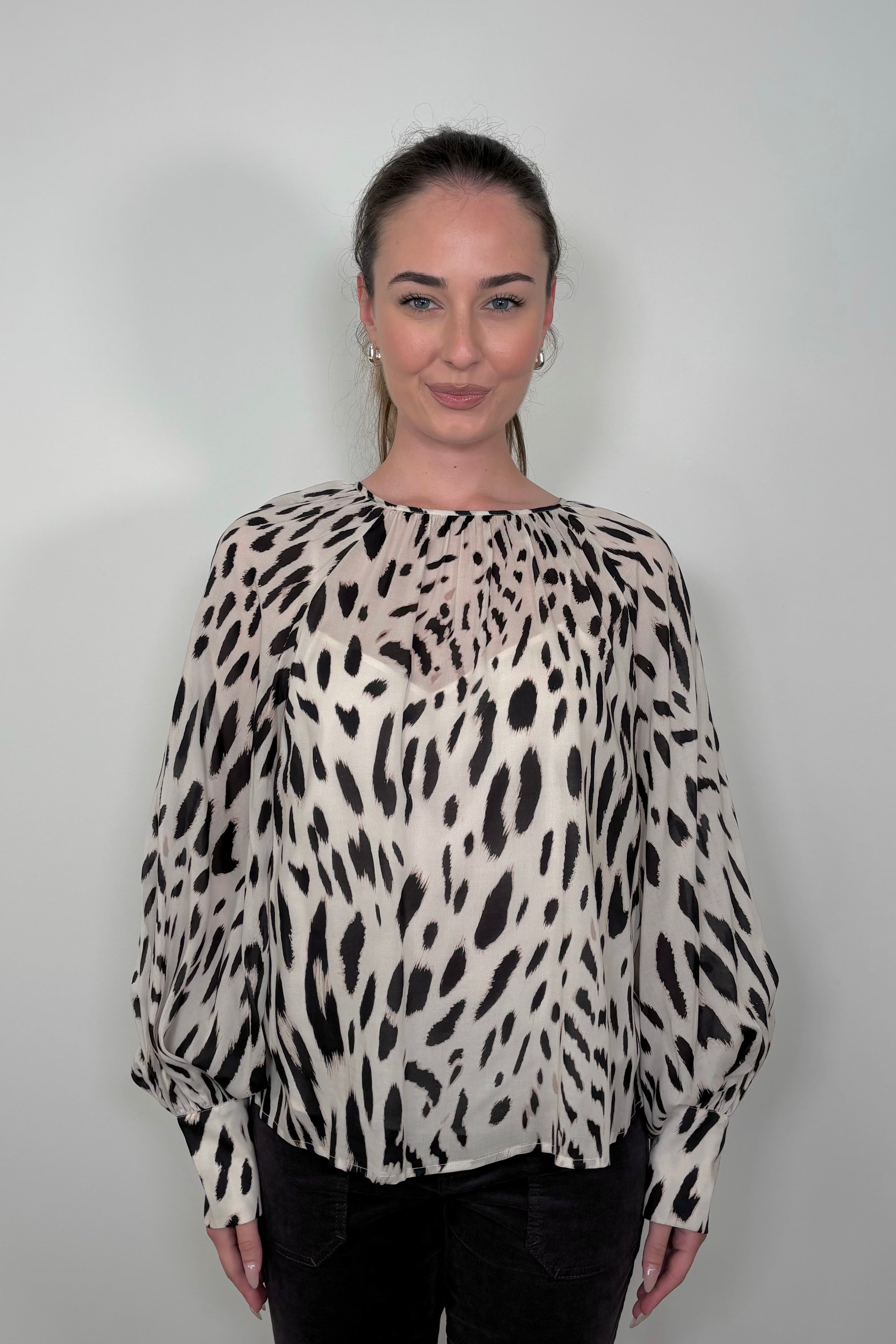 Front view of woman wearing a sheer printed blouse with a cami underneath