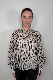 Front view of woman wearing a sheer printed blouse with a cami underneath