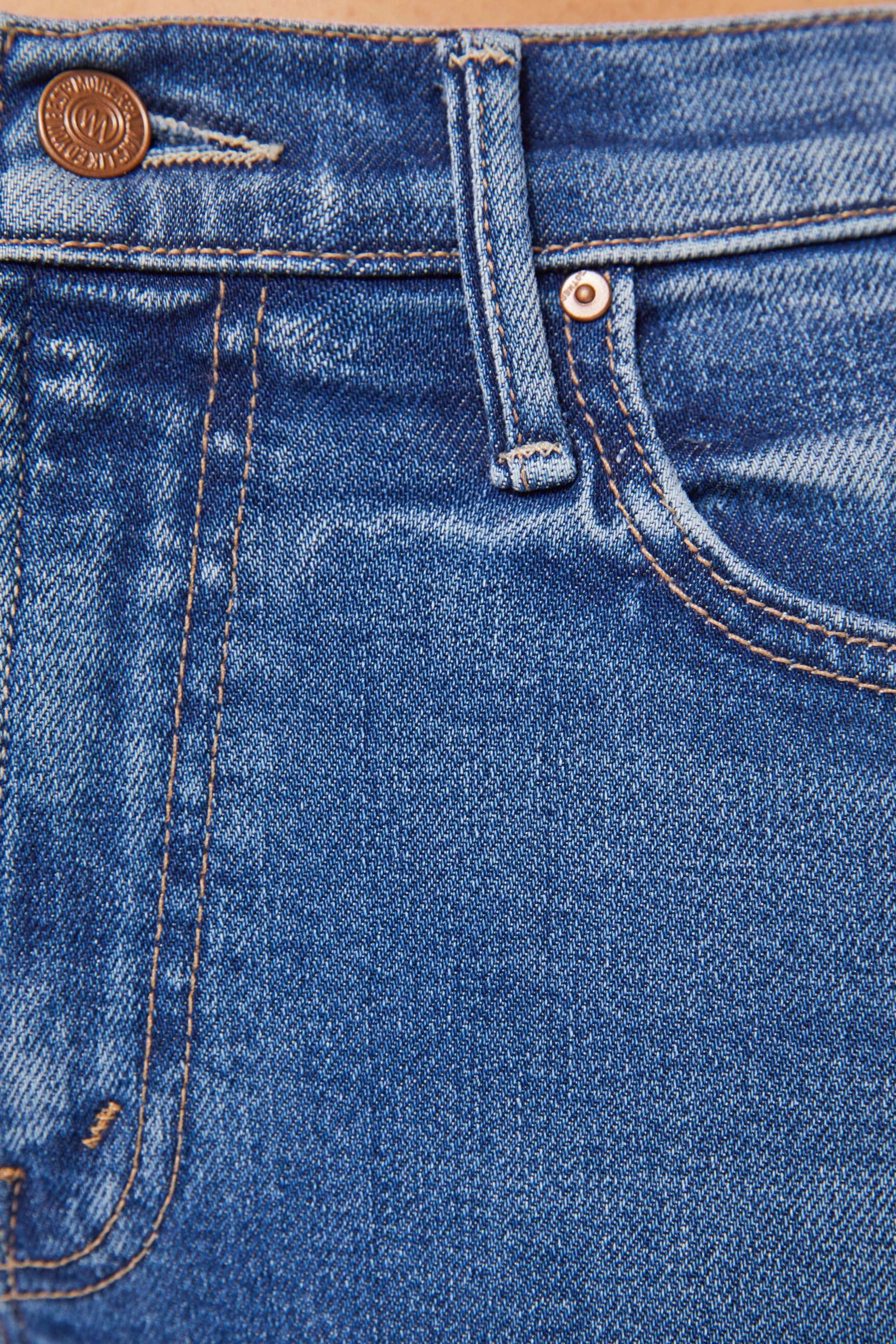 Front zoom in view of a person wearing blue mid-rise waist and a narrow flare leg jean