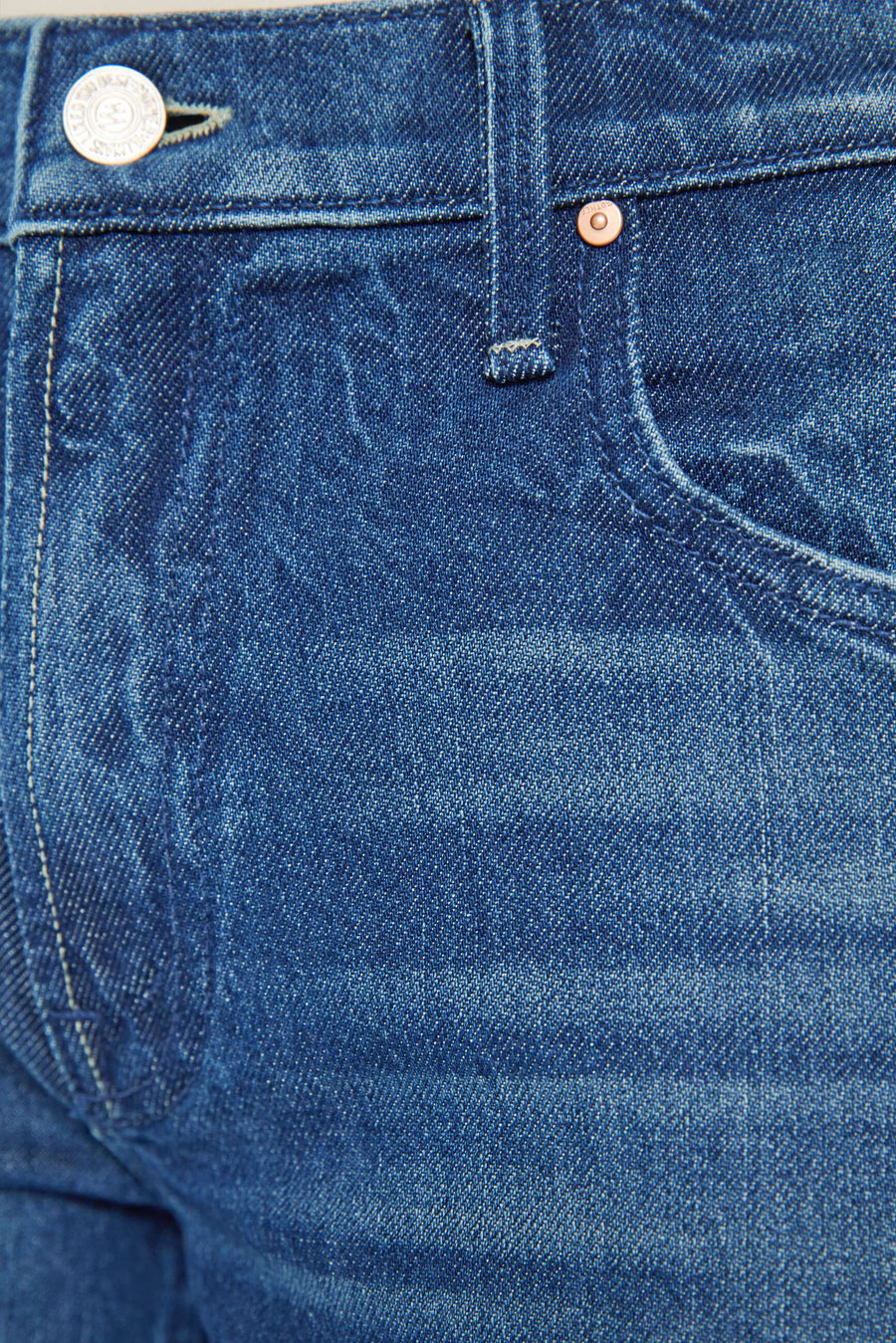 Close-up of blue denim fabric with a button and zipper