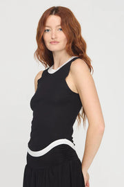 Woman wearing a black sleeveless rib knit tank top with white trim