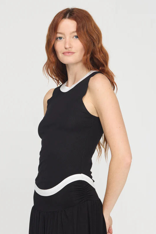Woman wearing a black sleeveless rib knit tank top with white trim