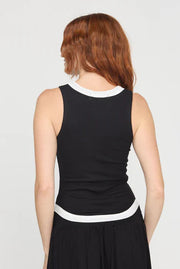 Woman wearing a black sleeveless rib knit tank top with white trim