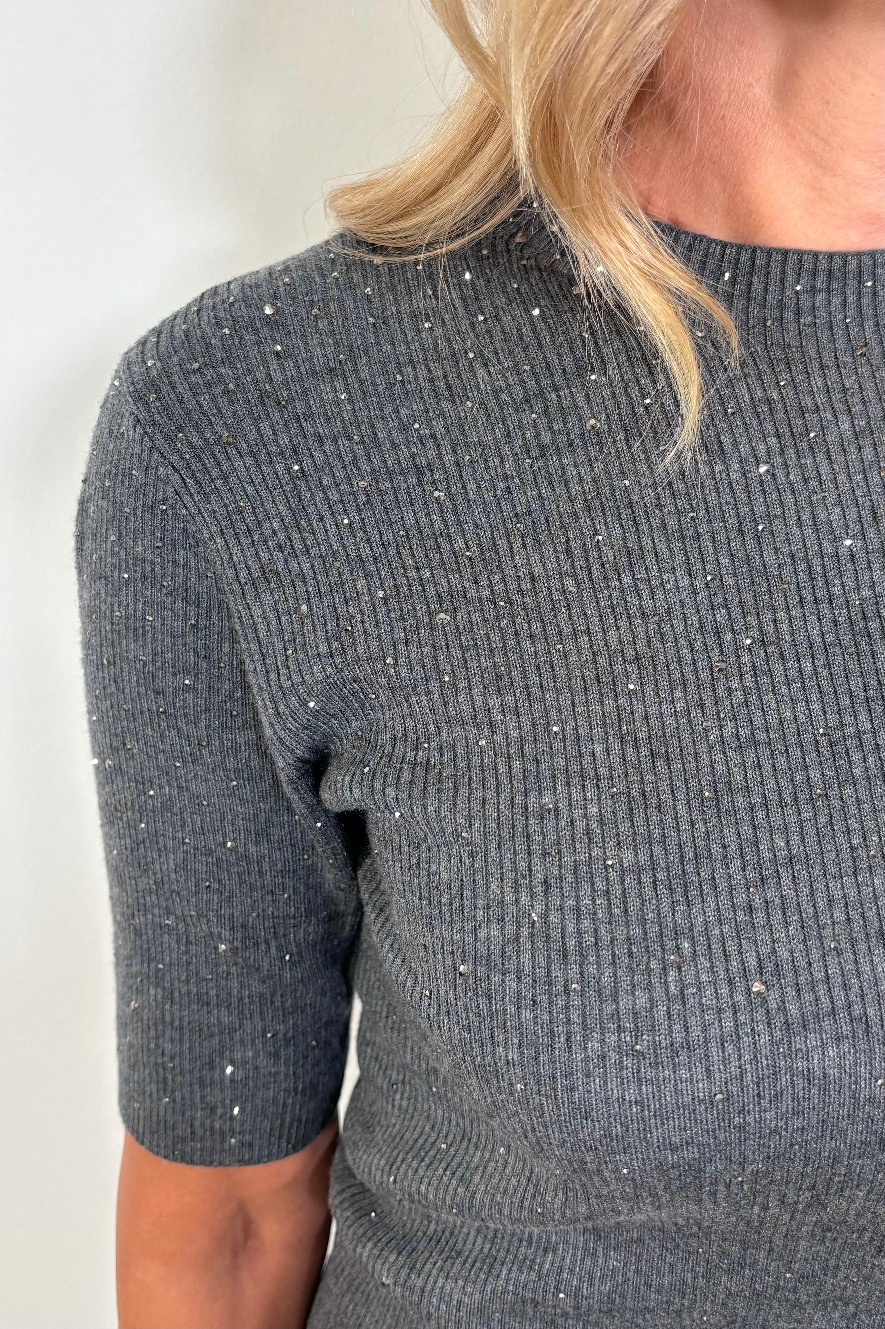 close up of the shoulder of a woman wearing a black ribbed tee with crystal embellishments 