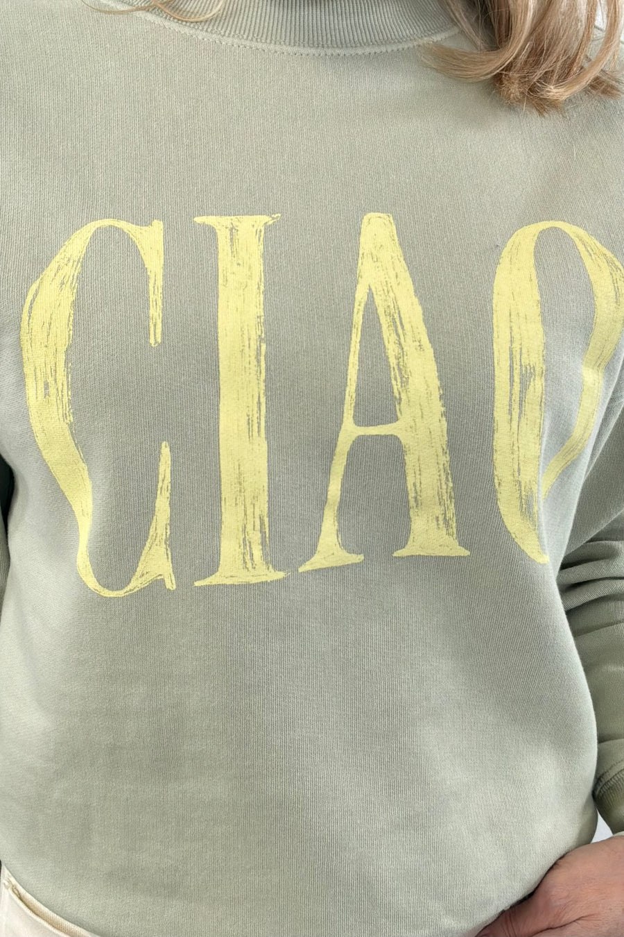Close up of Woman wearing a matcha green pullover with " ciao " detail  