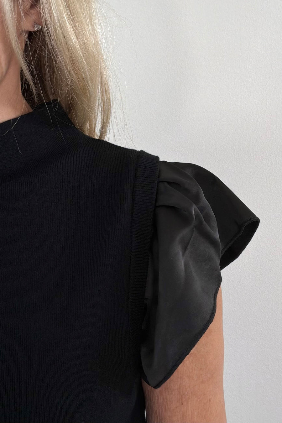close-up of a  black sweater top with ruffle satin cap sleeves