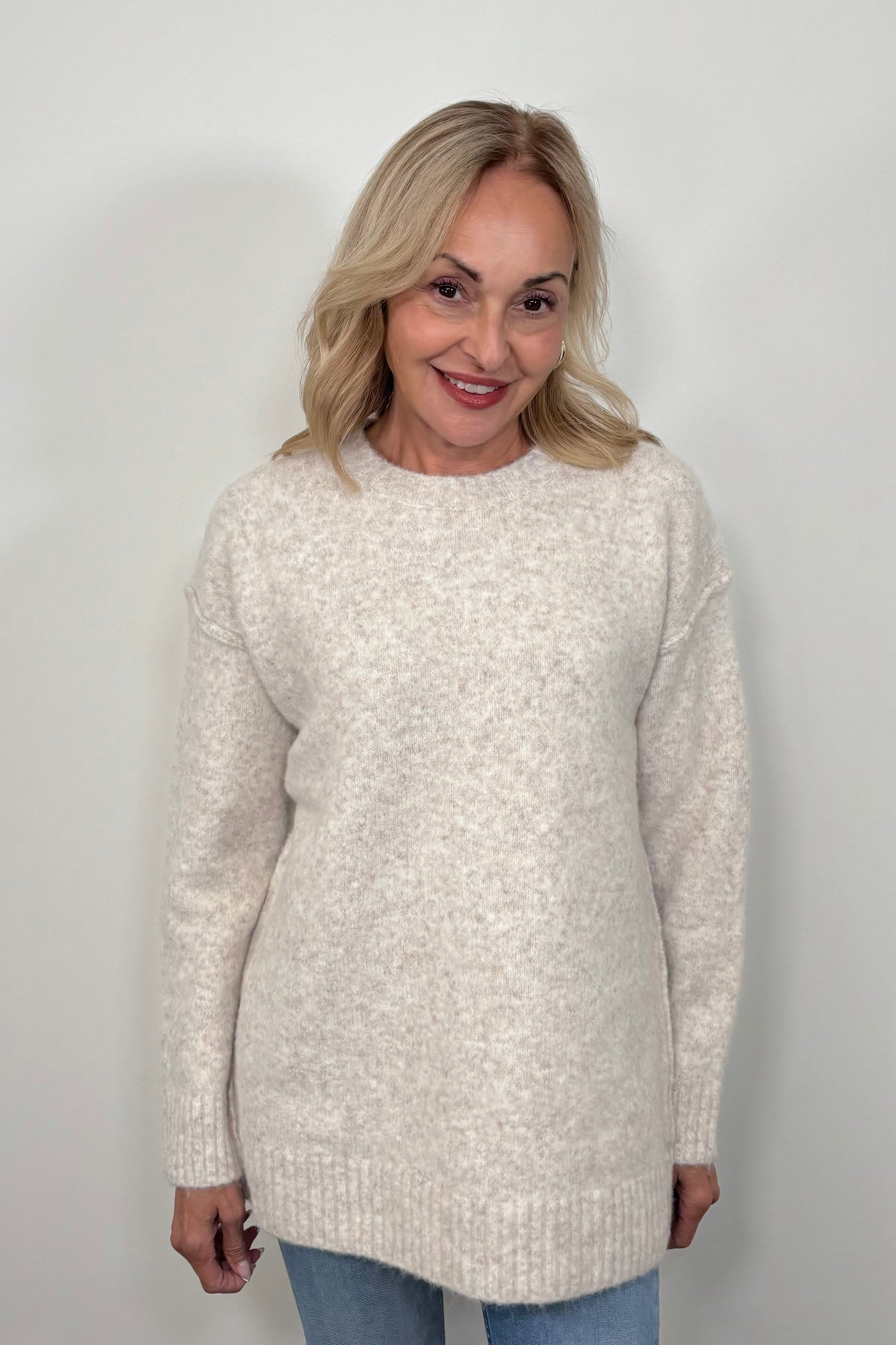 Front view of woman wearing an oatmeal coloured oversized knit sweater