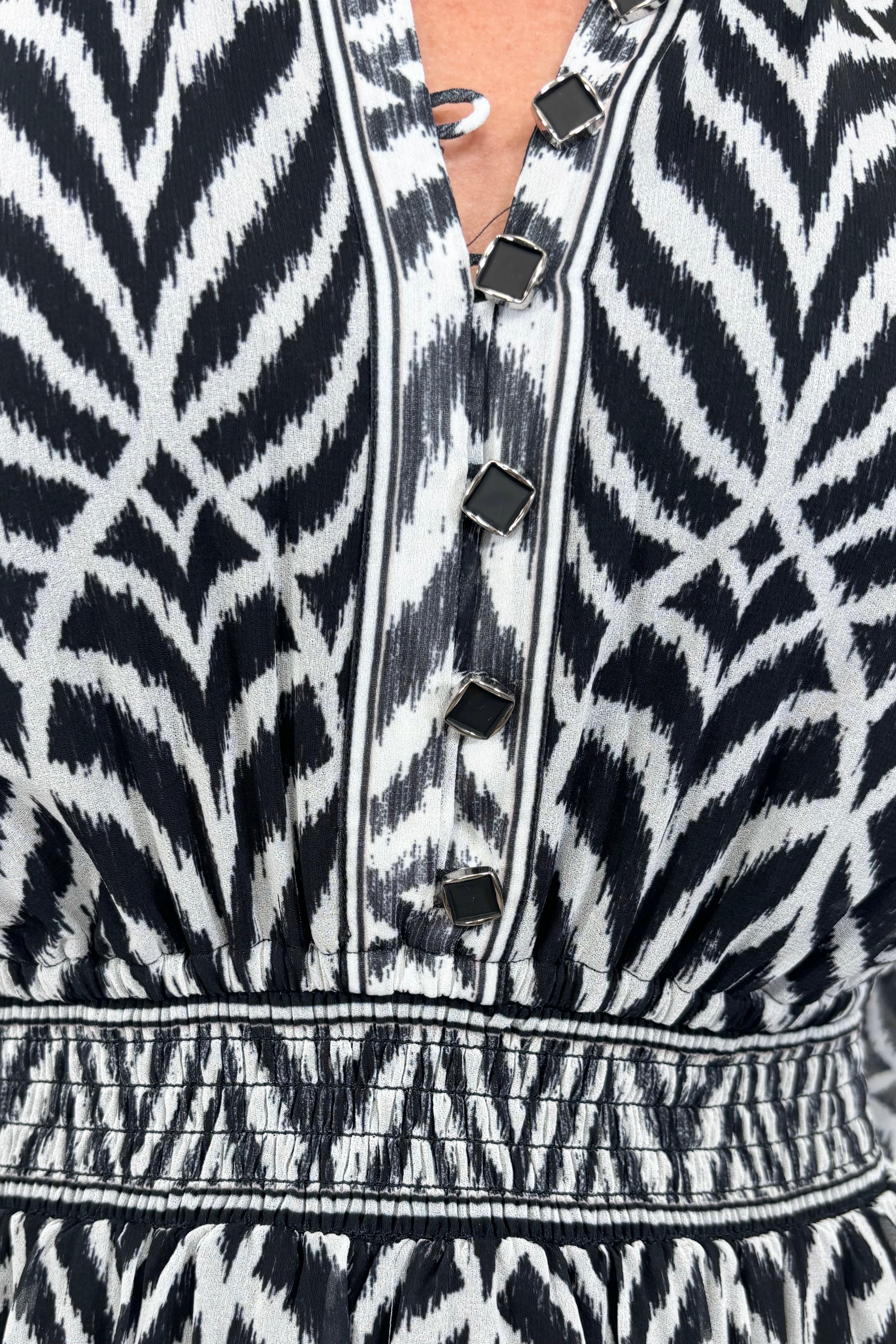 Close up view of woman wearing a dress with a smocked elastic waist and neckline with black and white stripes 