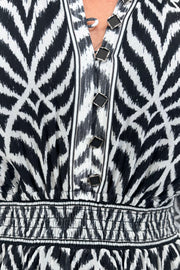 Close up view of woman wearing a dress with a smocked elastic waist and neckline with black and white stripes 
