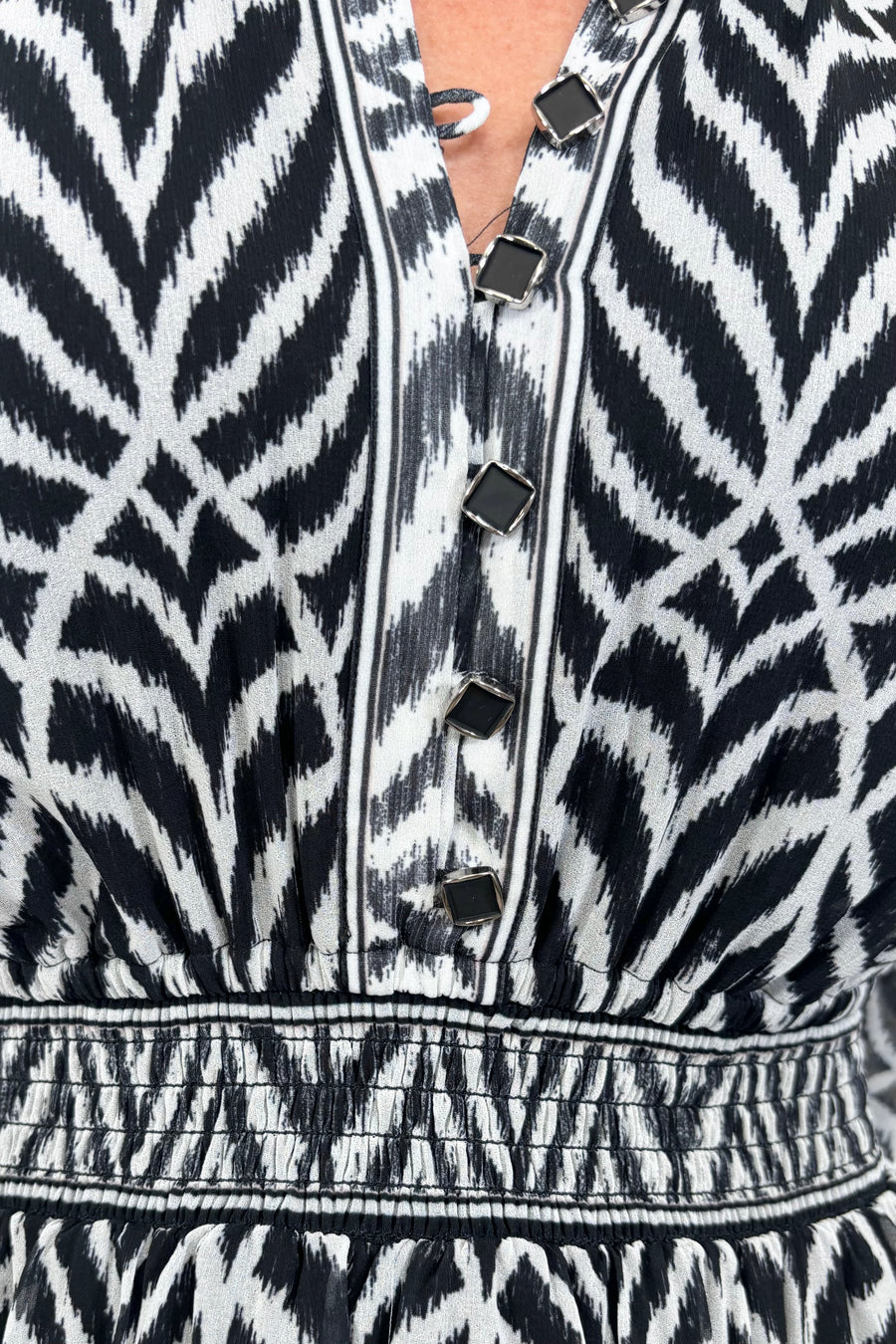 Close up view of woman wearing a dress with a smocked elastic waist and neckline with black and white stripes 