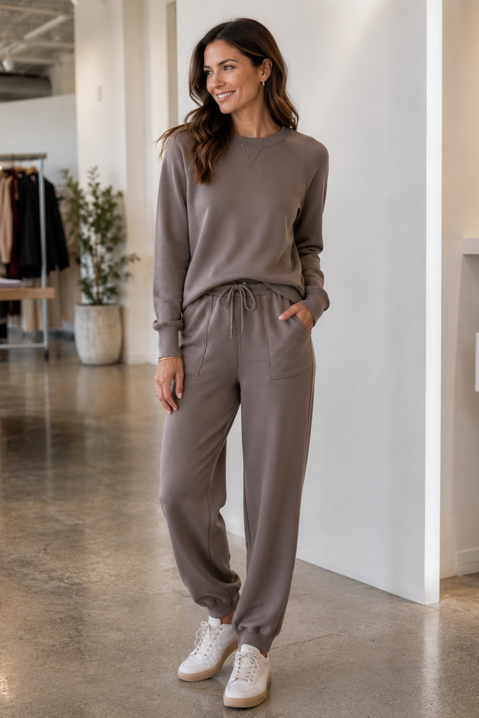 A woman modeling a matching taupe lounge set consisting of  jogger pants with a drawstring waist