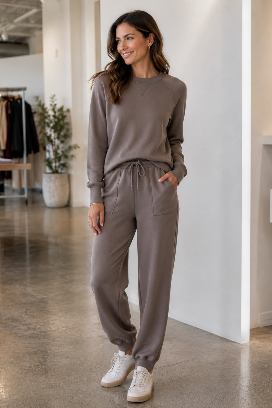 A woman modeling a matching taupe lounge set consisting of  jogger pants with a drawstring waist