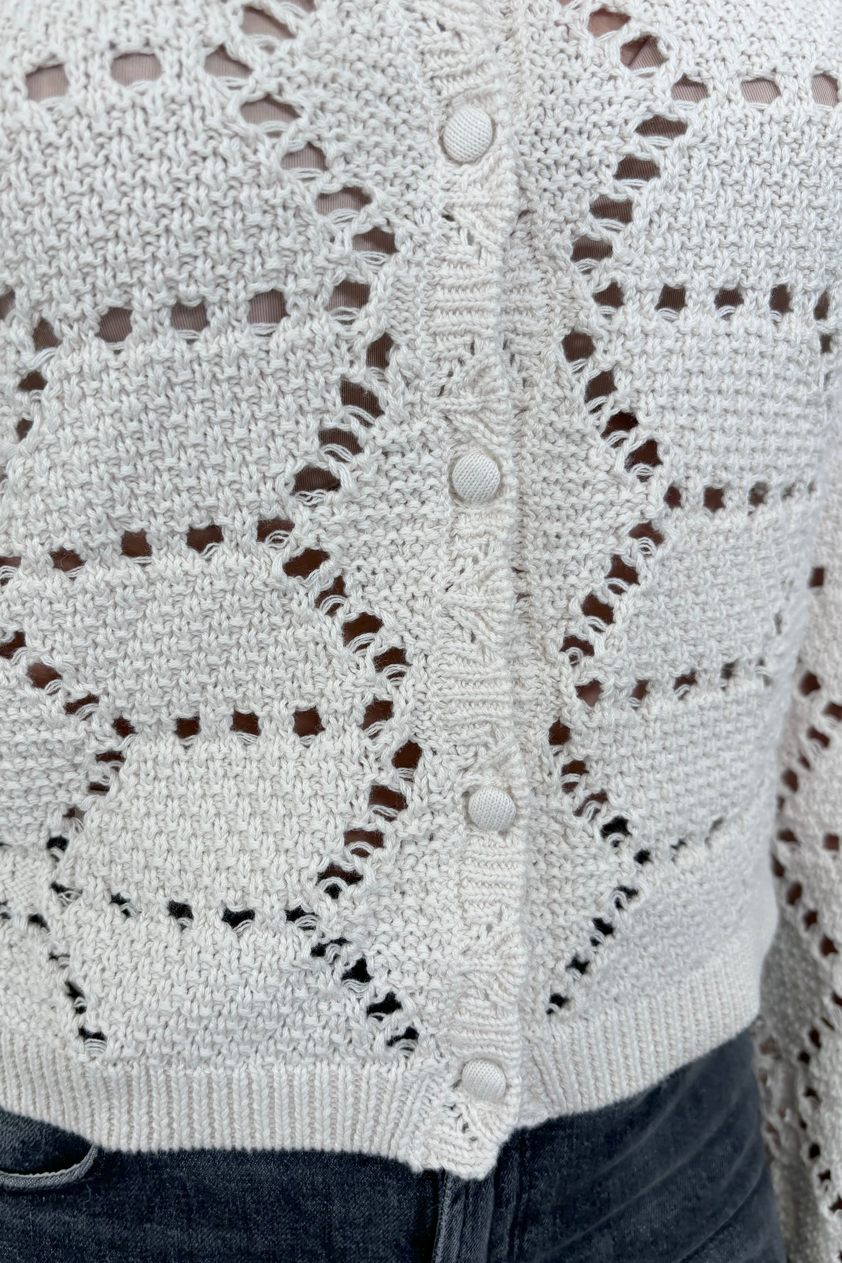 Close up view of woman wearing an off white knitted cardigan 