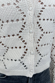 Close up view of woman wearing an off white knitted cardigan 