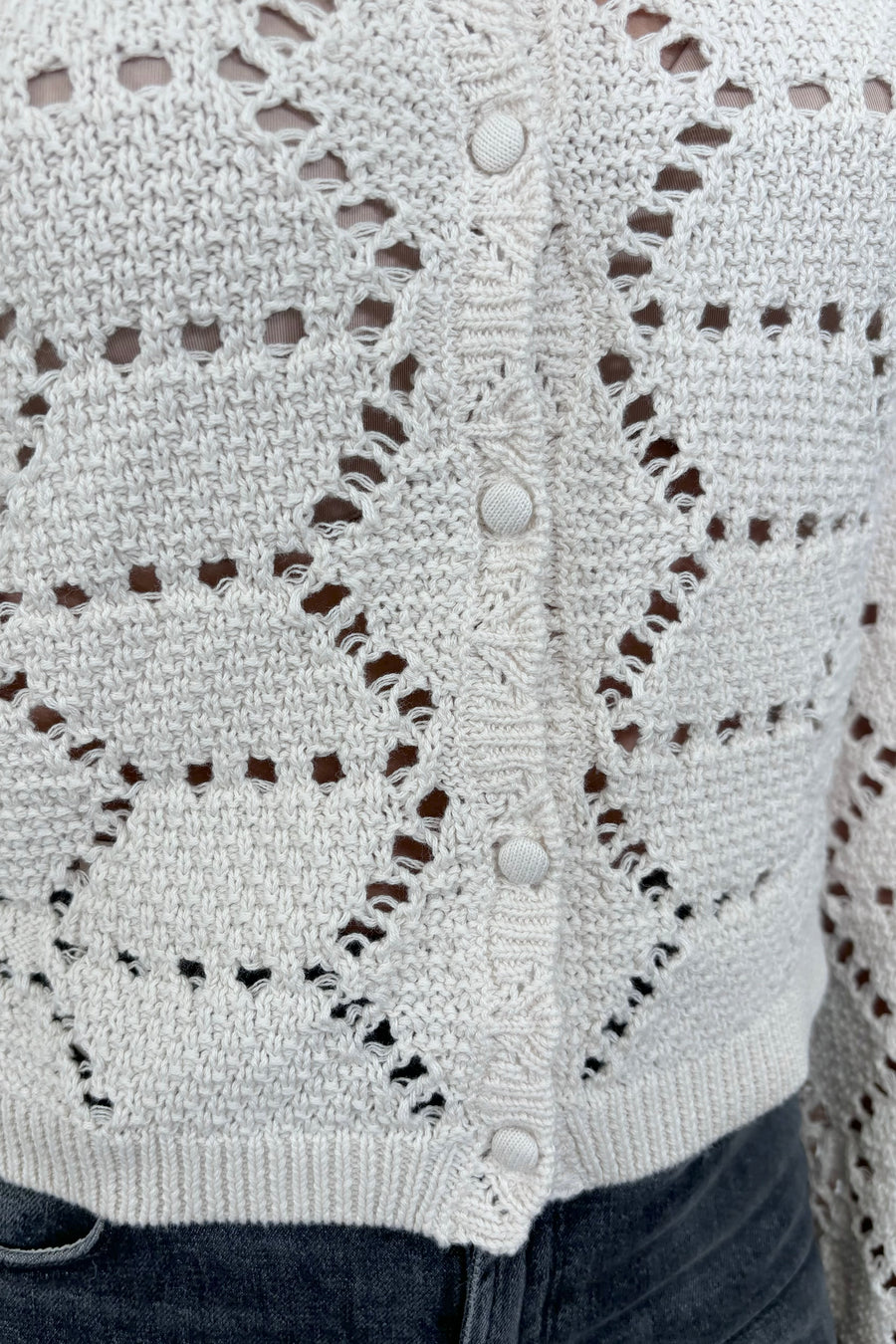 Close up view of woman wearing an off white knitted cardigan 