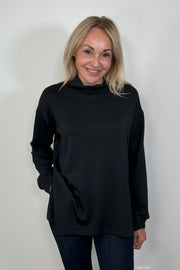 Front facing woman wearing a black boxy turtleneck top