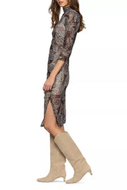 Woman wearing a patterned dress with a high slit and beige knee-high boots on a white background