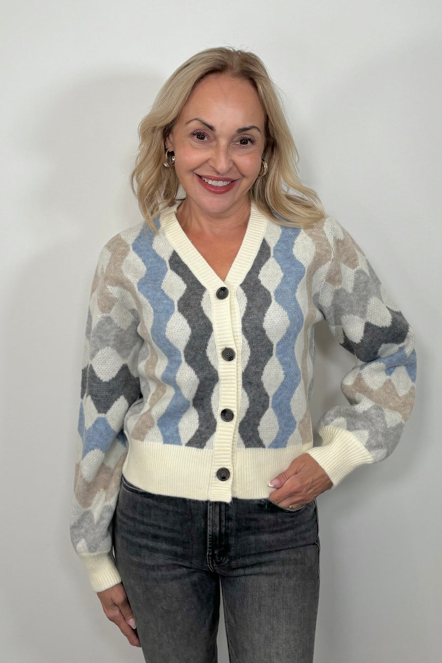 Front view of woman wearing a cardigan with blouson sleeved and a multicoloured waive design