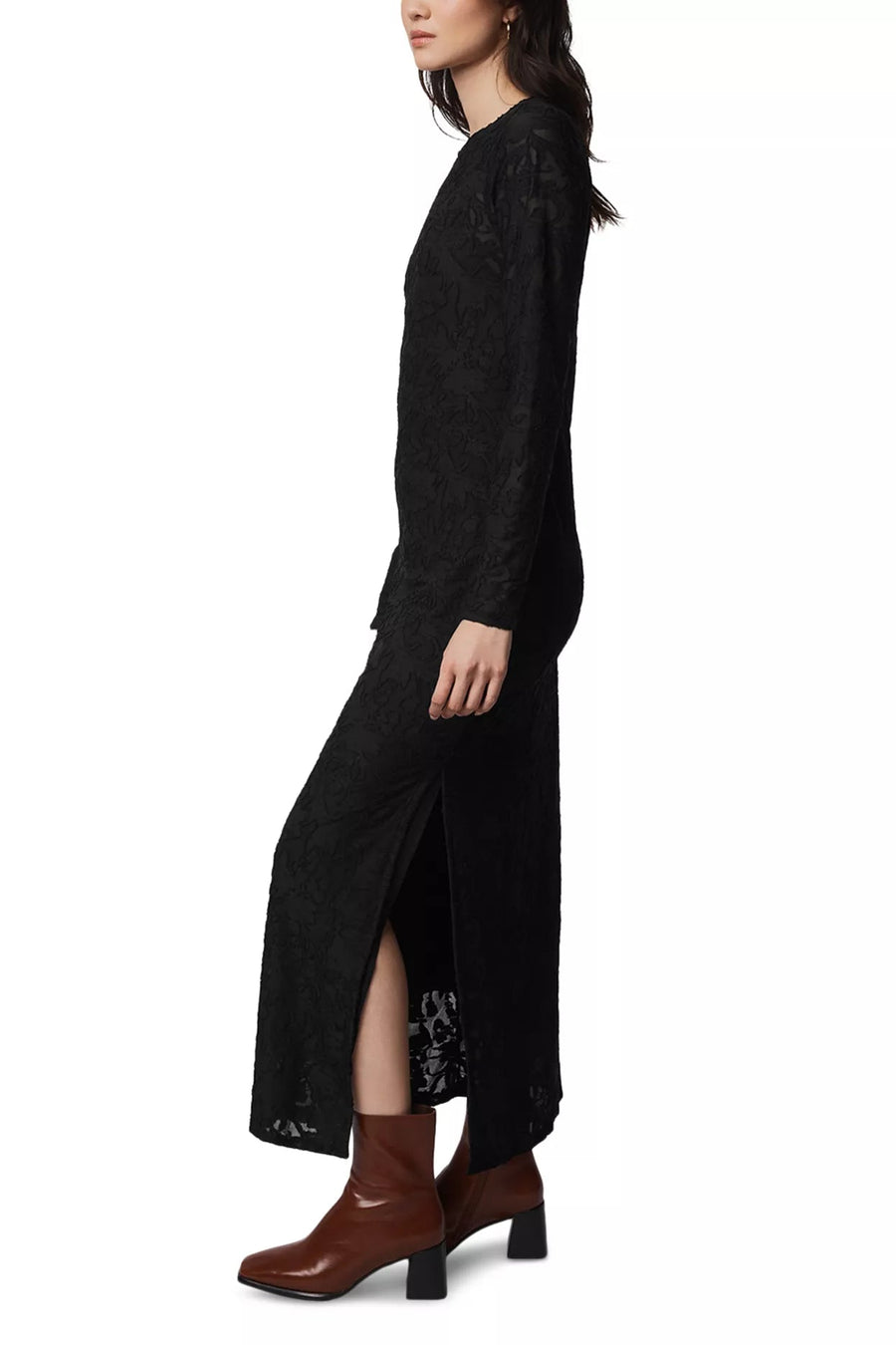 Woman wearing a long black dress with a slit, standing against a white background