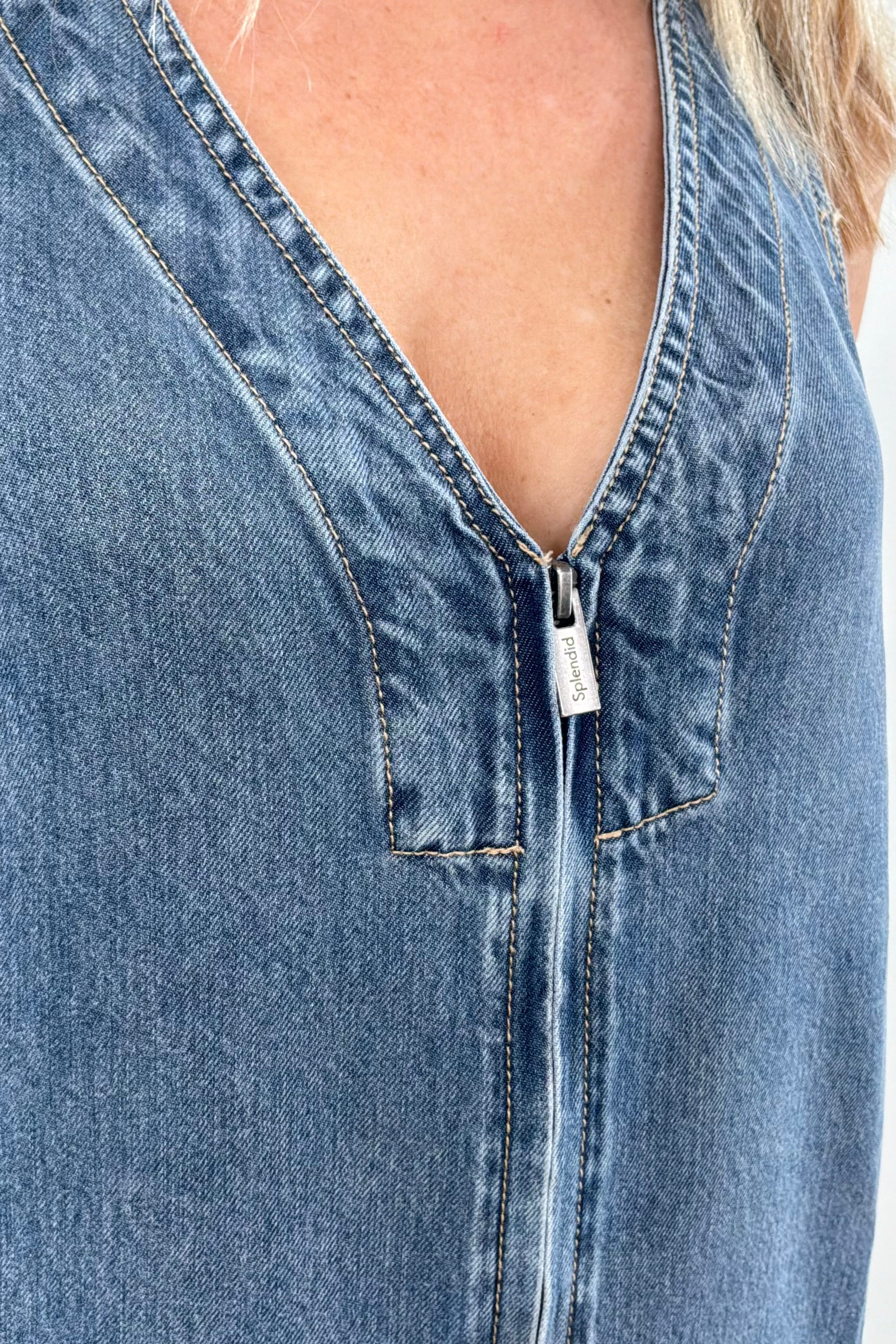 Sleeveless light wash denim mini dress with a V-neck and front seam detail, close up