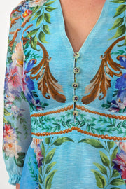 Close up of woman wearing a turquoise chiffon floral midi dress