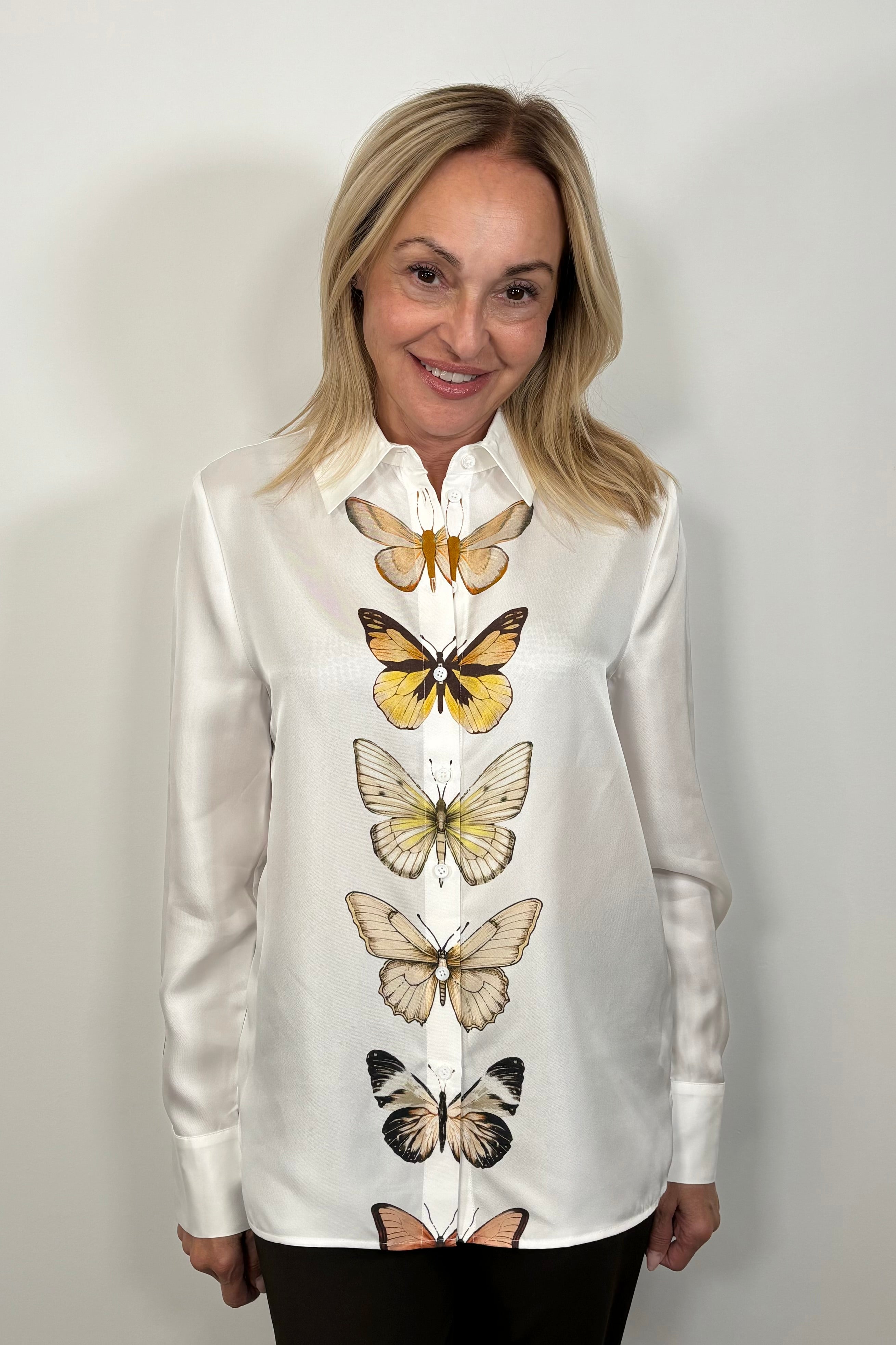 Front view of woman wearing a butterfly patterned button up silk shirt 