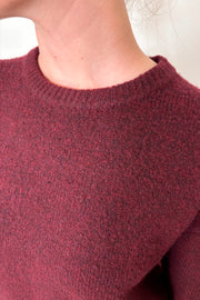 Close-up view of woman wearing a wine coloured crew-neck sweater 