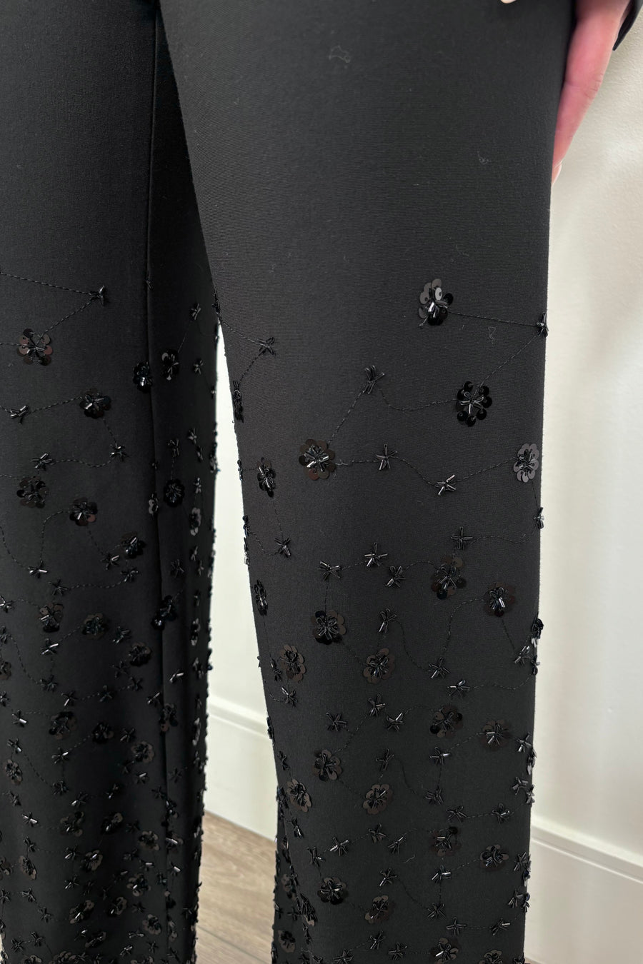 Black pants with floral embellishments on a plain background