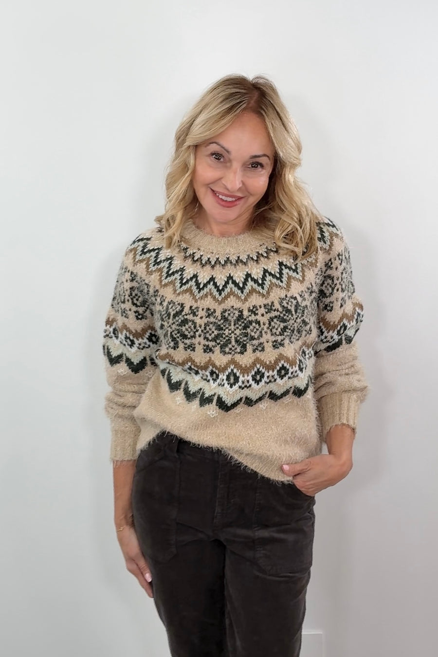 Woman wearing a patterned sweater against a plain background