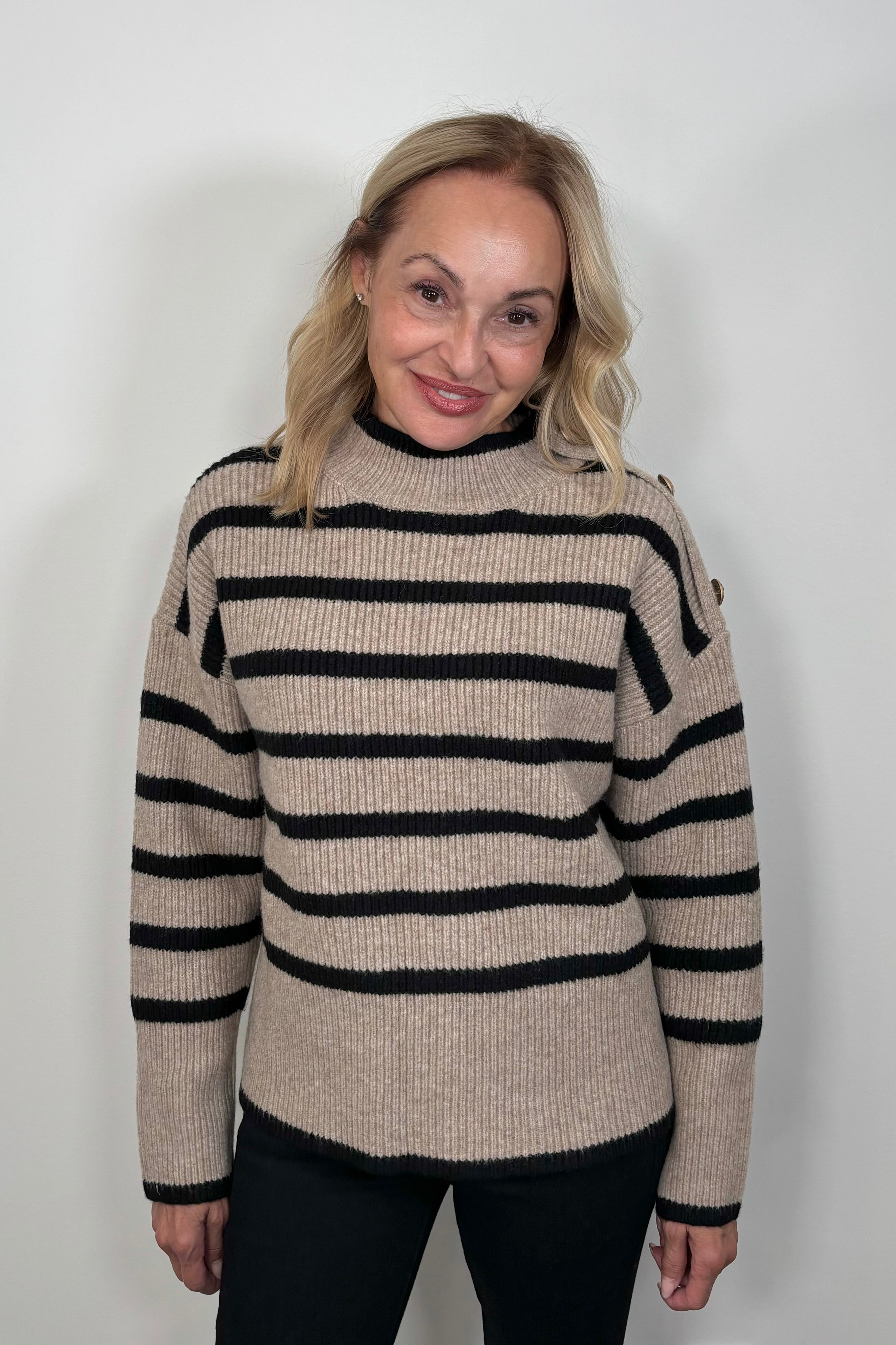 woman wearing a walnut coloured sweater with stripes and buttons on the left shoulder