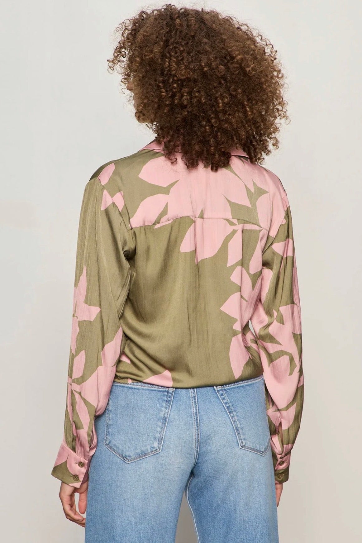 Back view of Woman wearing a dark green and pink printed top