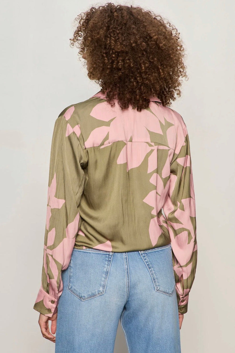 Back view of Woman wearing a dark green and pink printed top