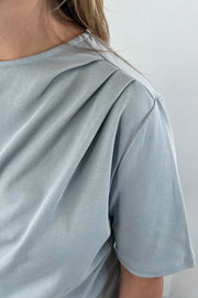 Woman wearing a blue gray t-shirt with twist detail